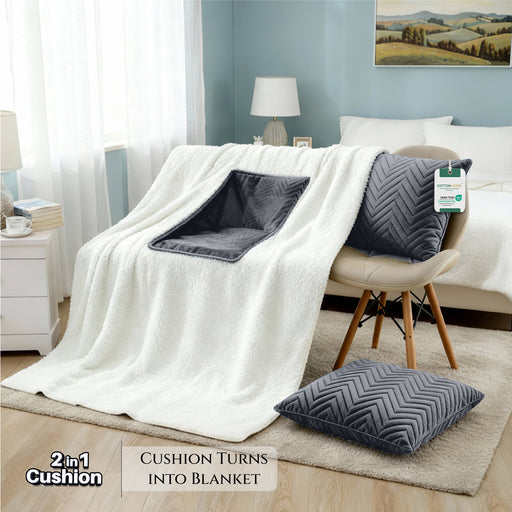 White blanket with gray cushion and pillow on a chair in a room setting.